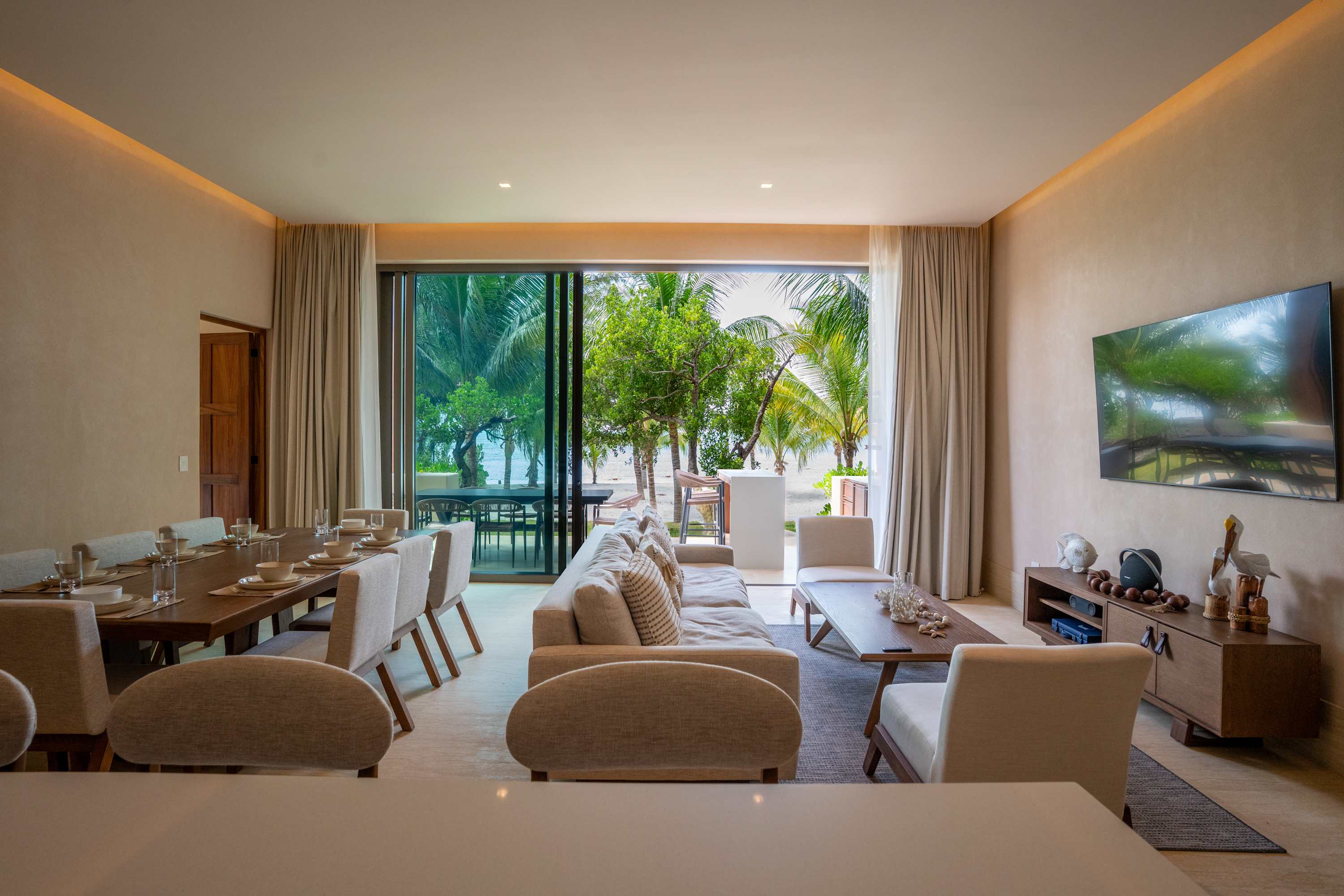 A luxurious open-concept living and dining area with a view of a tropical beach.