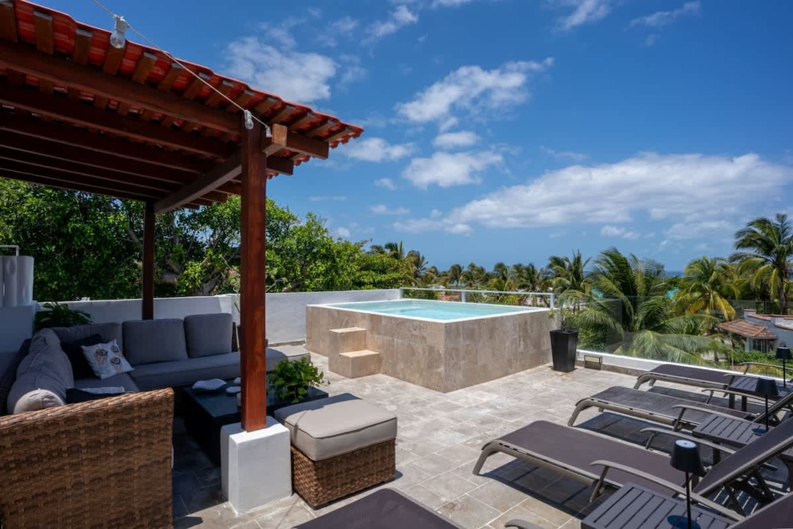 A rooftop patio with a plunge pool, lounge chairs, and a covered seating area.