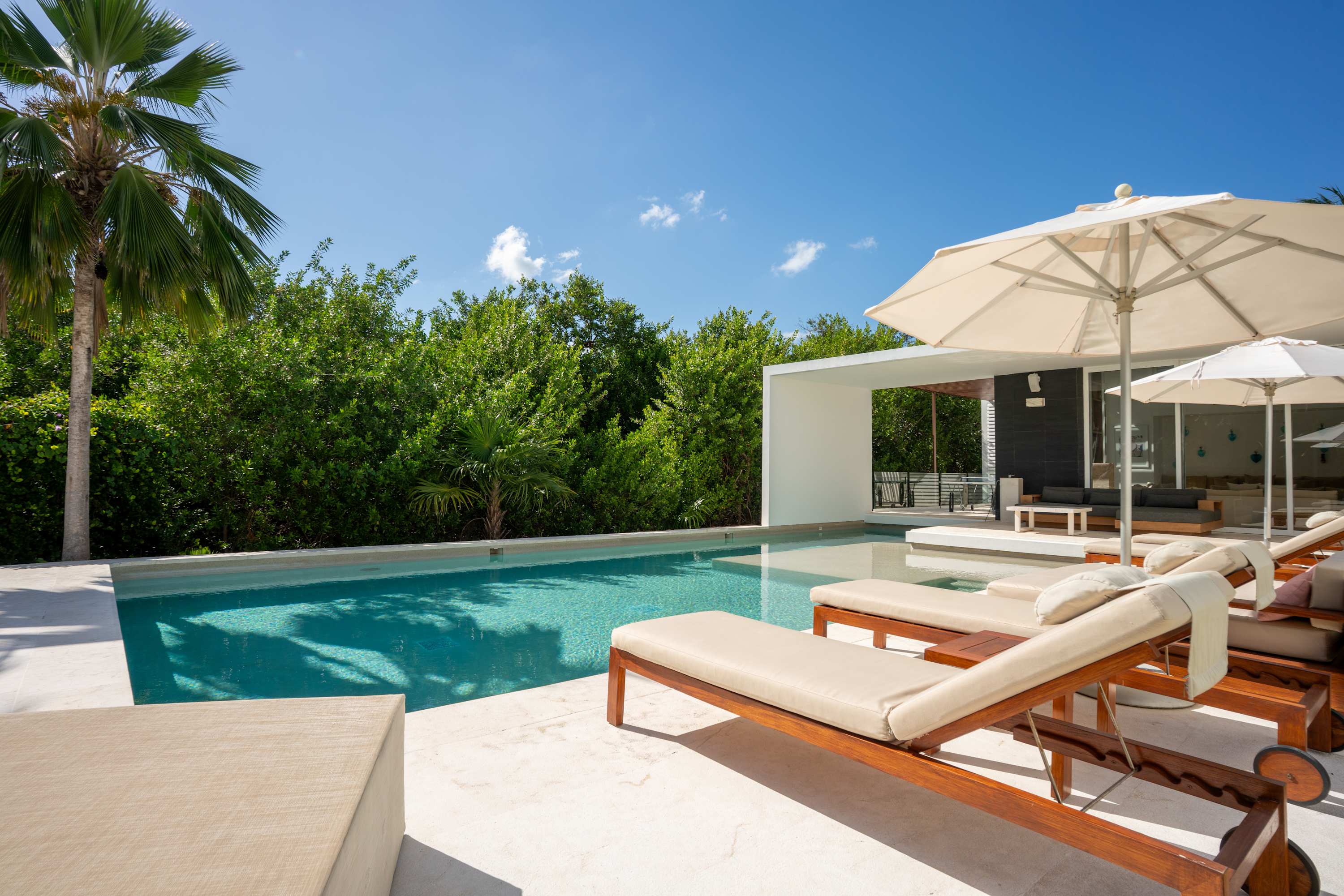 Luxury outdoor lounge chairs and umbrellas beside a swimming pool.
