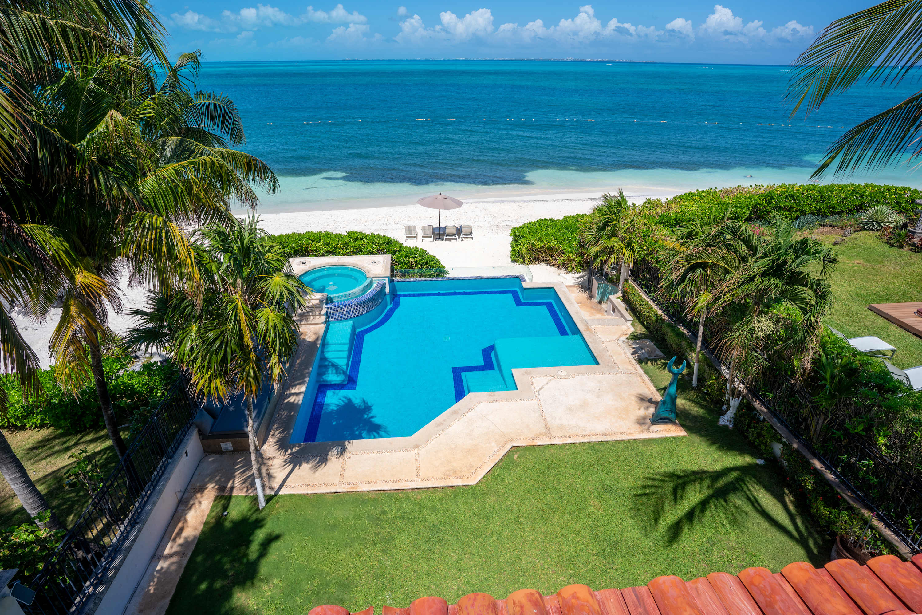 Luxury beach villa with pool, hot tub, palm trees, and ocean view.